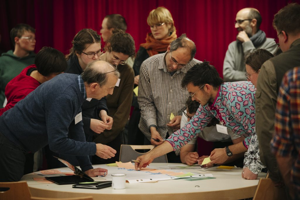Menschen sprechen über einen Tisch gebeugt miteinander